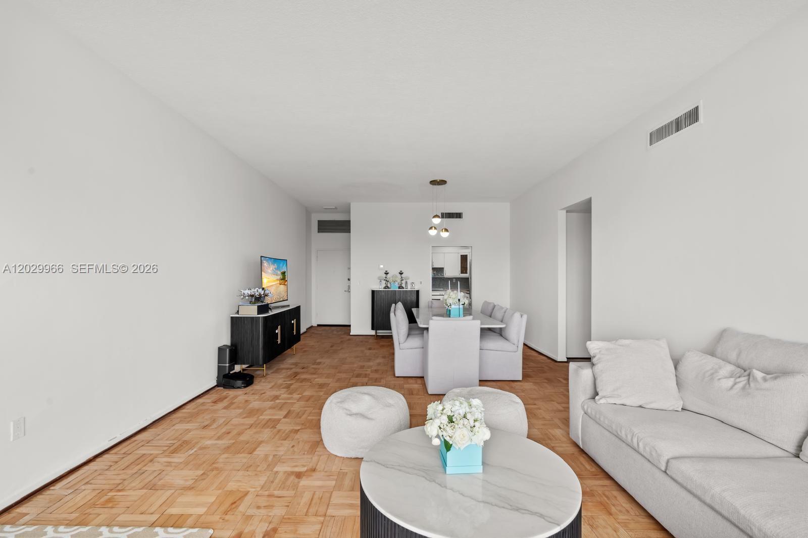 This open-concept living and dining area features light-colored furniture, white walls, and parquet flooring — 9341 E Bay Harbor Dr # B, Bay Harbor Islands FL 33154, BAY HARBOR ISLANDS, FL