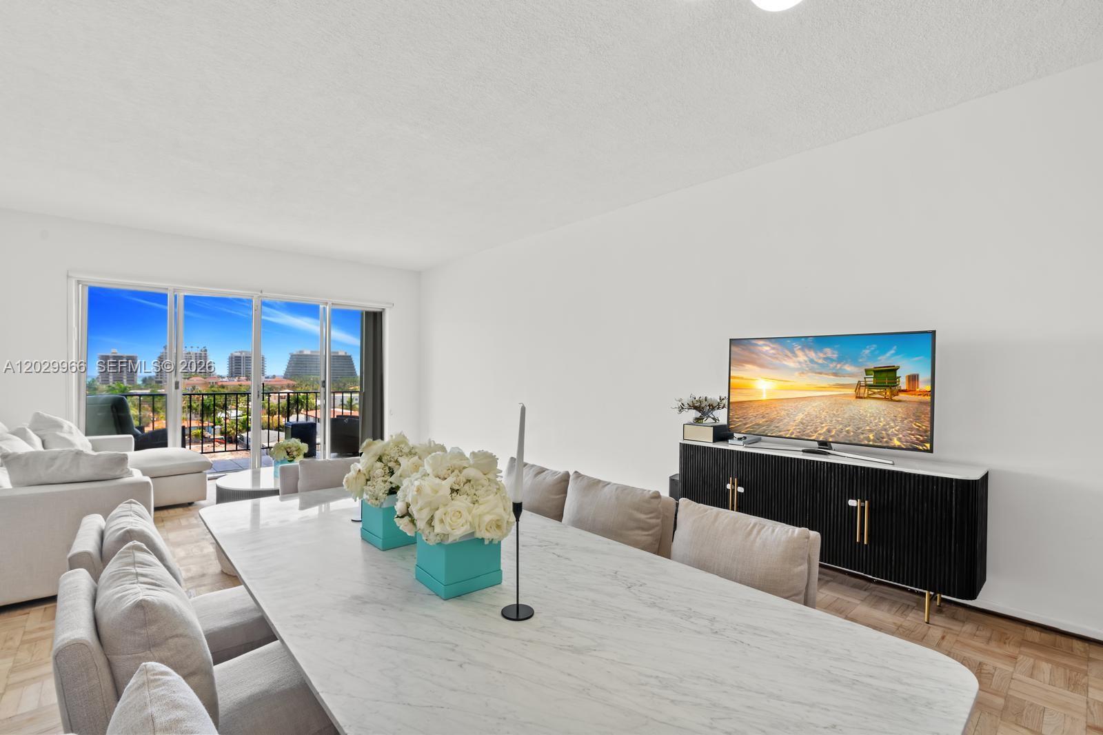 A dining area with a marble table and chairs sits before a living room balcony — 9341 E Bay Harbor Dr # B, Bay Harbor Islands FL 33154, BAY HARBOR ISLANDS, FL