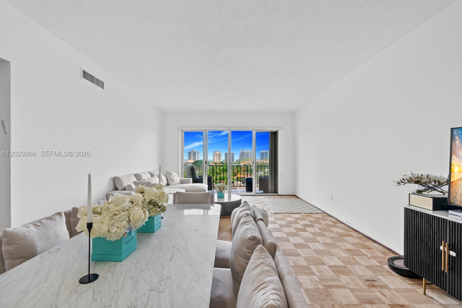 A dining area with a marble table leads into a living room with balcony access — 9341 E Bay Harbor Dr # B, Bay Harbor Islands FL 33154, BAY HARBOR ISLANDS, FL