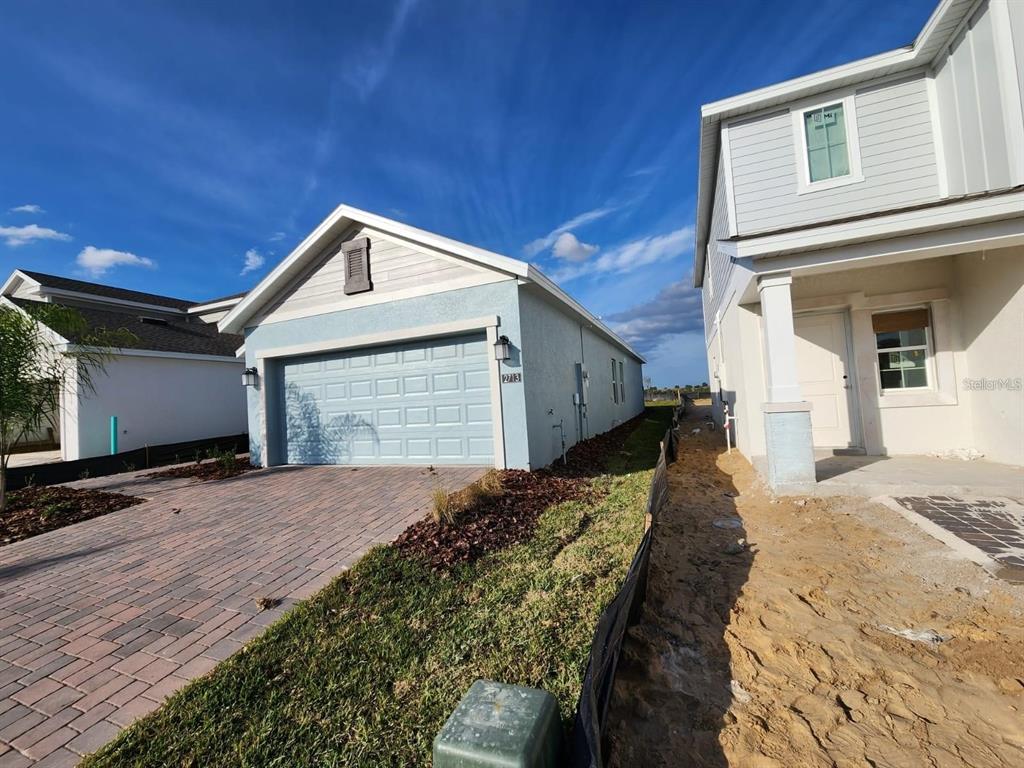 A light blue house with a two-car garage sits next to a neighboring home under construction — 2713 RUNNERS CIRCLE, CLERMONT, FL