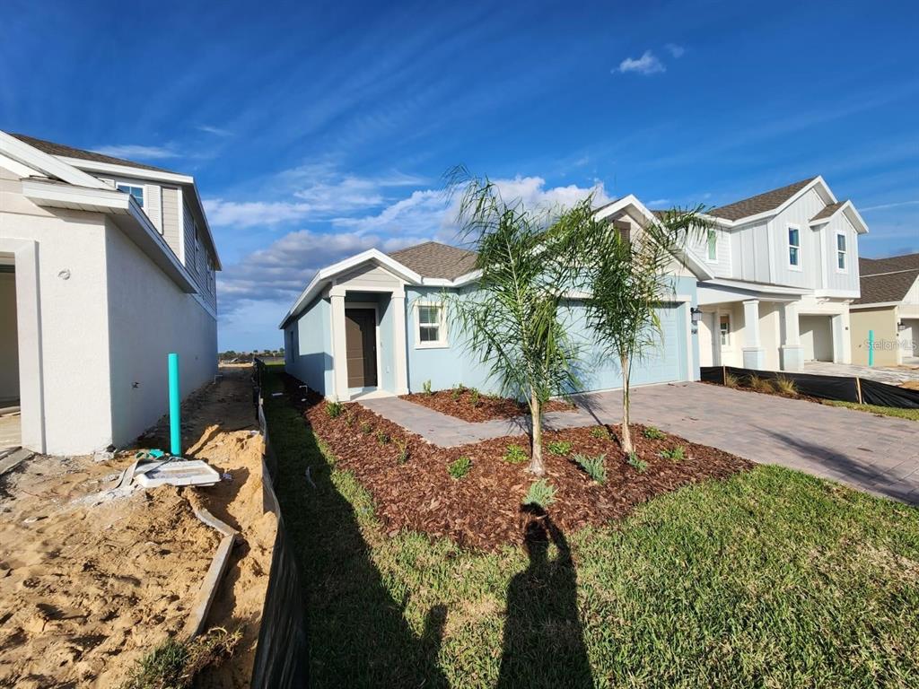 A light blue single-story house with a paved driveway and two small palm trees — 2713 RUNNERS CIRCLE, CLERMONT, FL