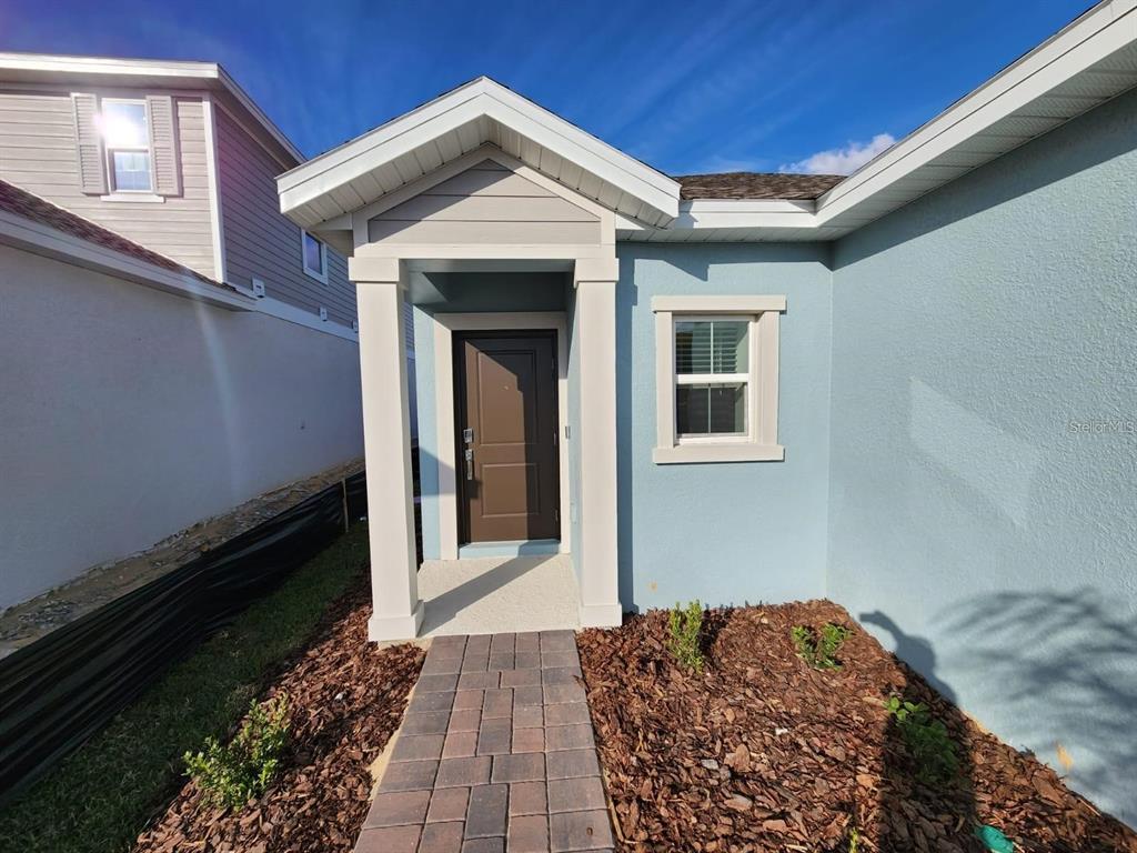 A light blue house exterior features a covered entryway with a brown door and walkway — 2713 RUNNERS CIRCLE, CLERMONT, FL