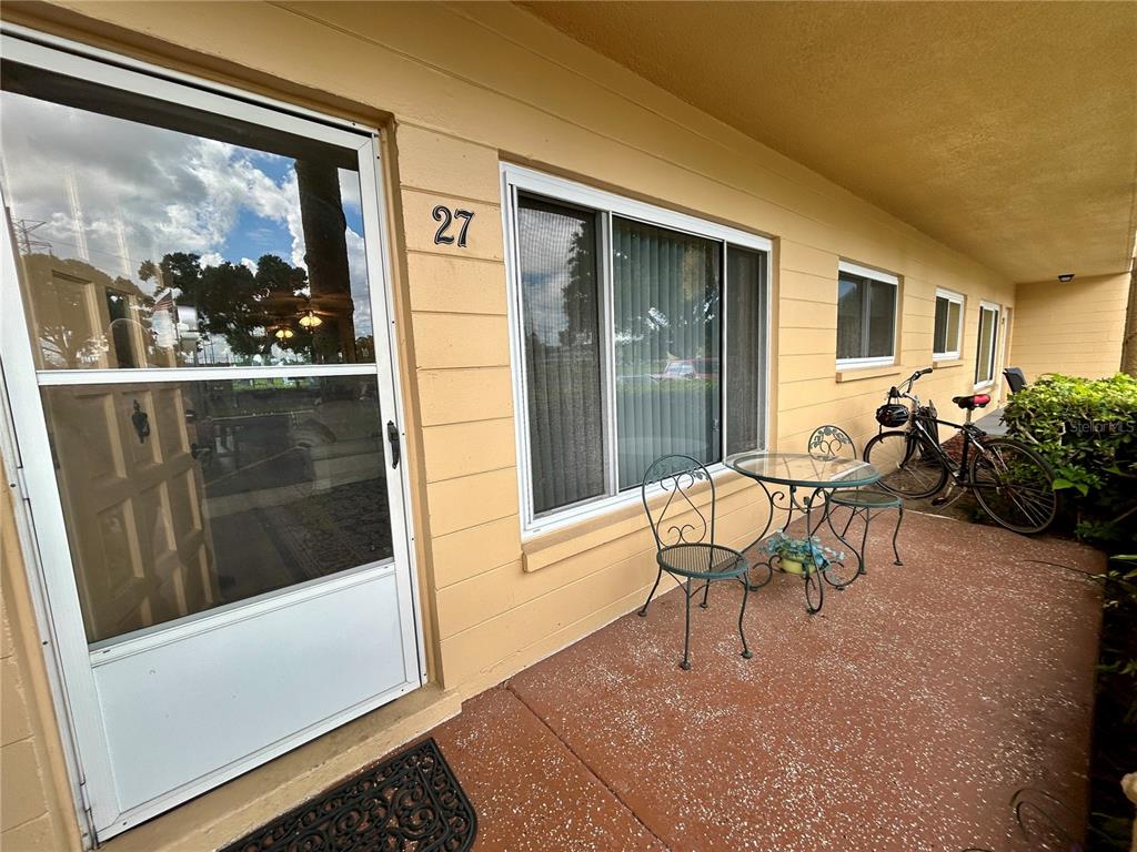 A patio with a table, two chairs, and a bicycle sits outside a unit entrance — 2467 FINLANDIA LANE UNIT 27, CLEARWATER, FL