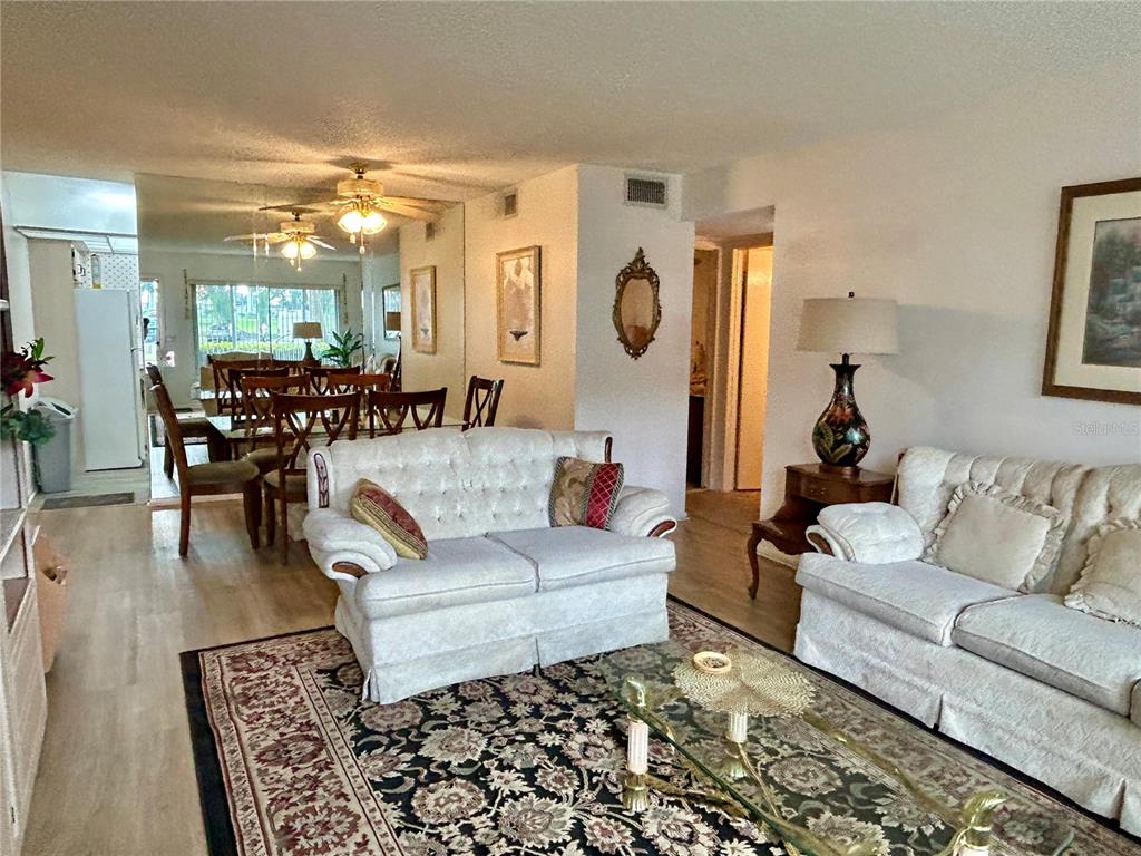 A living room with two white sofas, a patterned rug, and a mirrored dining area — 2467 FINLANDIA LANE UNIT 27, CLEARWATER, FL