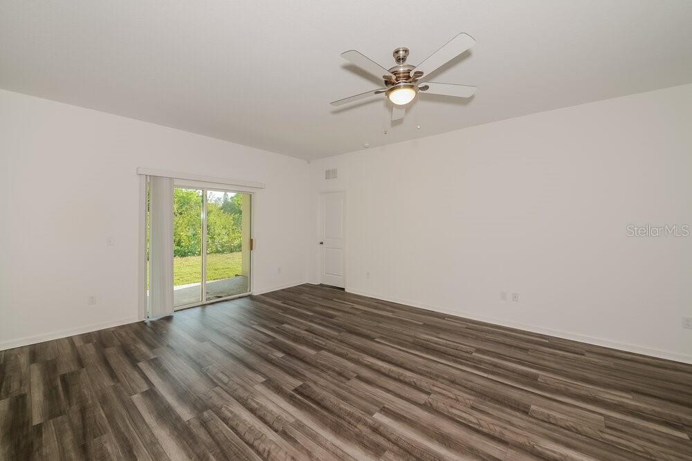 An empty living room features wood-look flooring, a ceiling fan, and a sliding glass door — 996 OCEAN SPRAY DRIVE, RUSKIN, FL
