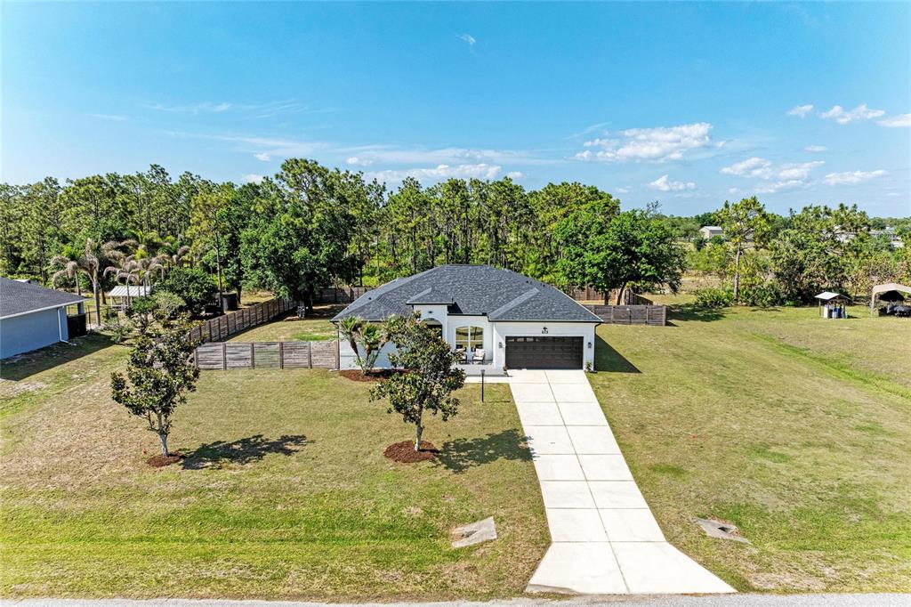 A single-story house with a dark roof and a concrete driveway sits on a lawn — 26013 81ST DRIVE E, MYAKKA CITY, FL