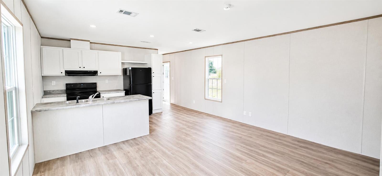 A kitchen with white cabinets and a black refrigerator opens into a living area — 820 Maryland Avenue, Clewiston FL 33440, CLEWISTON, FL
