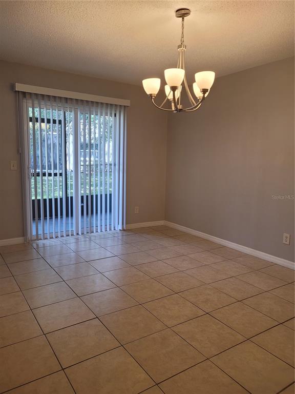 A dining room with beige tile flooring, a chandelier, and sliding glass doors to a patio — 2417 BARLEY CLUB DRIVE UNIT 5, ORLANDO, FL
