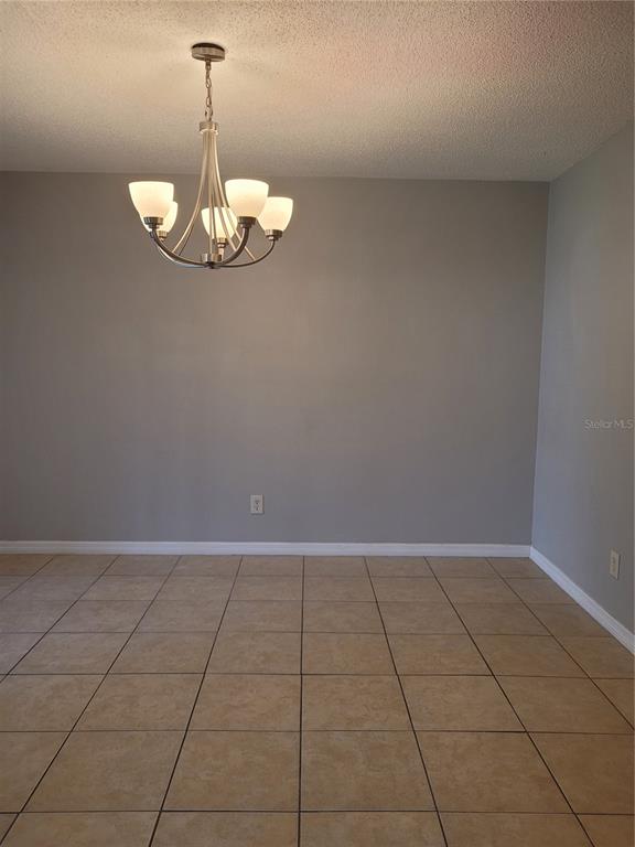 A dining area features light gray walls, a modern chandelier, and tan tile flooring — 2417 BARLEY CLUB DRIVE UNIT 5, ORLANDO, FL