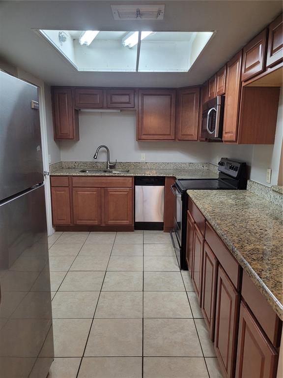 A kitchen features wood cabinets, granite countertops, stainless steel appliances, and a large ceiling skylight — 2417 BARLEY CLUB DRIVE UNIT 5, ORLANDO, FL