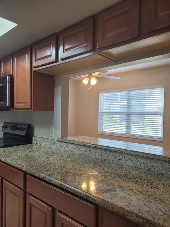 A kitchen with granite countertops and wood cabinets overlooks a dining area with a window — 2417 BARLEY CLUB DRIVE UNIT 5, ORLANDO, FL