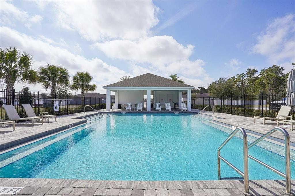 A rectangular swimming pool with a covered pavilion and lounge chairs under a blue sky — 3522 FERNANDA DRIVE, DELTONA, FL