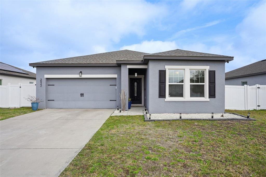 A gray, single-story suburban house features a two-car garage and a front-facing window — 3522 FERNANDA DRIVE, DELTONA, FL