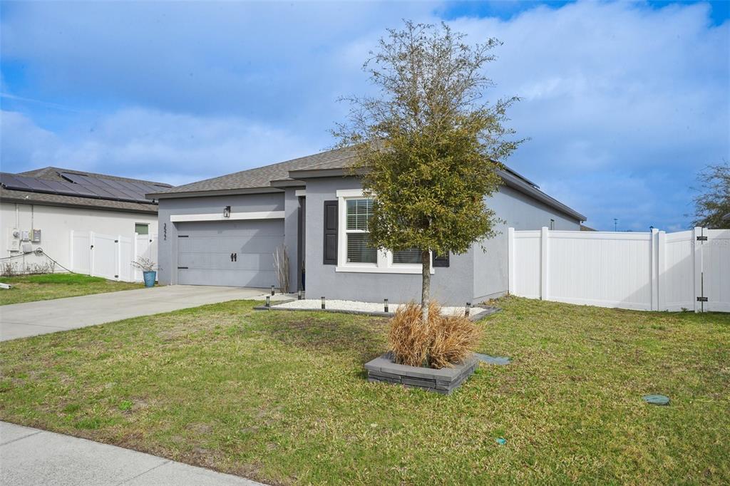 A single-story gray house with a two-car garage and a white vinyl privacy fence — 3522 FERNANDA DRIVE, DELTONA, FL