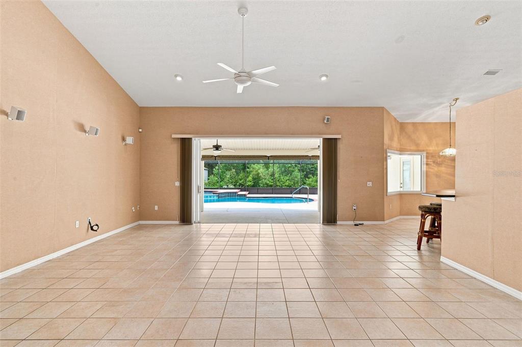 A spacious living area with tile floors, a ceiling fan, and sliding doors to a pool — 5928 N OAKMONT DRIVE, BEVERLY HILLS, FL