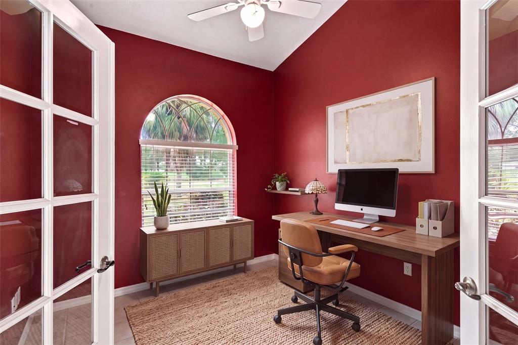 A home office features red walls, a wooden desk, a rattan cabinet, and an arched window — 5928 N OAKMONT DRIVE, BEVERLY HILLS, FL