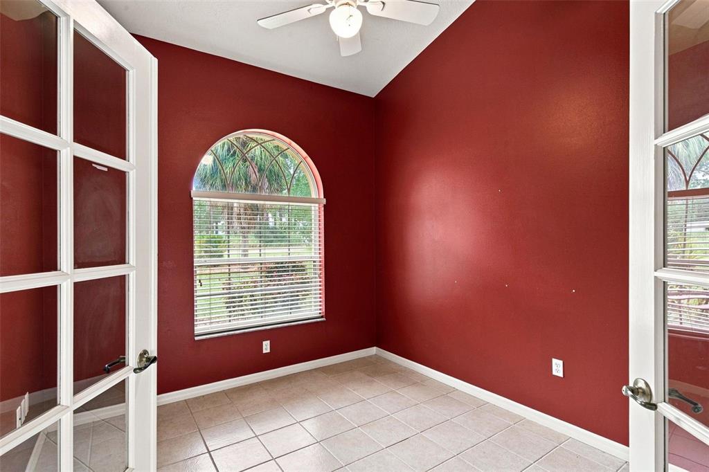 A room with red walls, tile flooring, a ceiling fan, and an arched window — 5928 N OAKMONT DRIVE, BEVERLY HILLS, FL