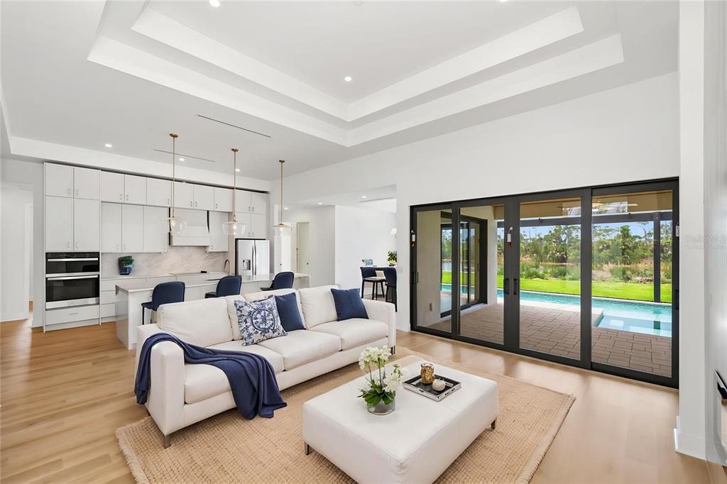 A modern open-concept living room and kitchen featuring white cabinetry, a pool, and sliding doors — 16692 LIGGETT CIRCLE, PORT CHARLOTTE, FL