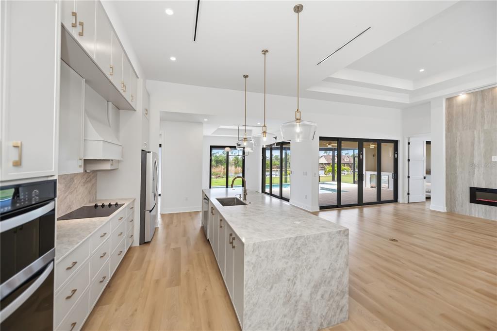 A modern kitchen features a large marble island, white cabinetry, and views of a pool — 16692 LIGGETT CIRCLE, PORT CHARLOTTE, FL