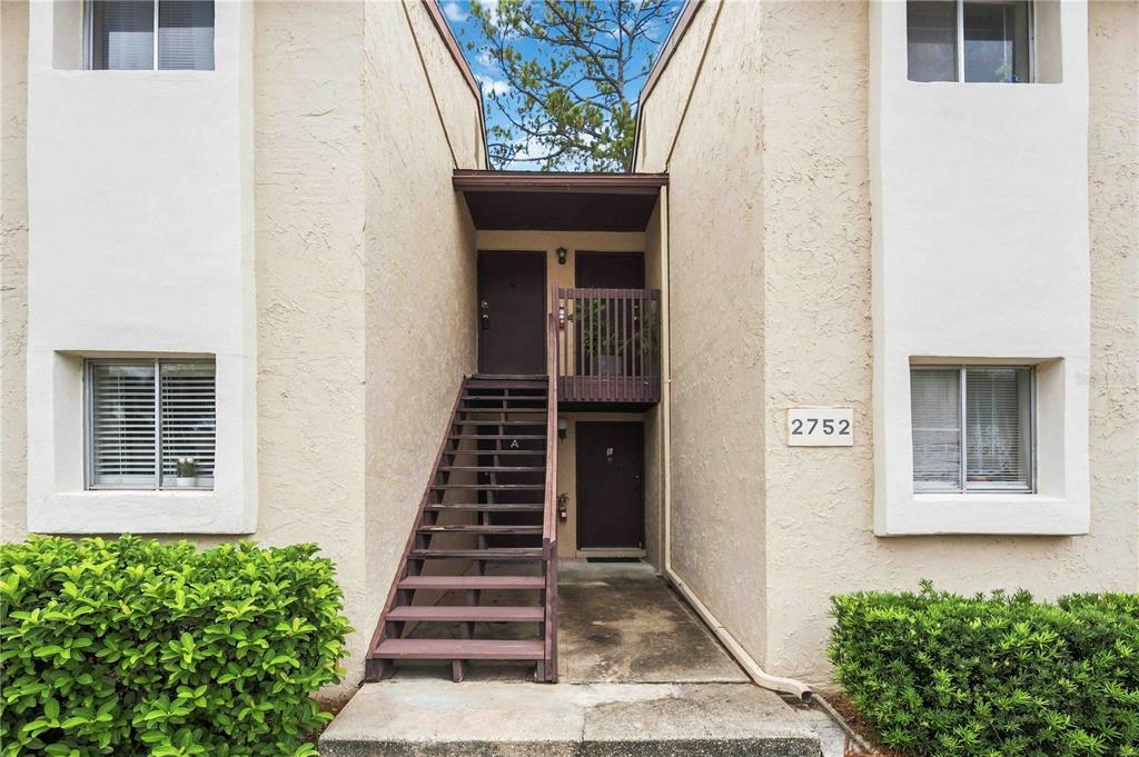 An exterior view of a two-story apartment building with a wooden staircase and balcony — 2752 HIDDEN LAKE BOULEVARD UNIT C, SARASOTA, FL