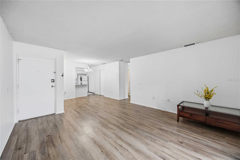 An open-concept living area features light wood-look flooring, white walls, and a glass-topped console table — 2752 HIDDEN LAKE BOULEVARD UNIT C, SARASOTA, FL