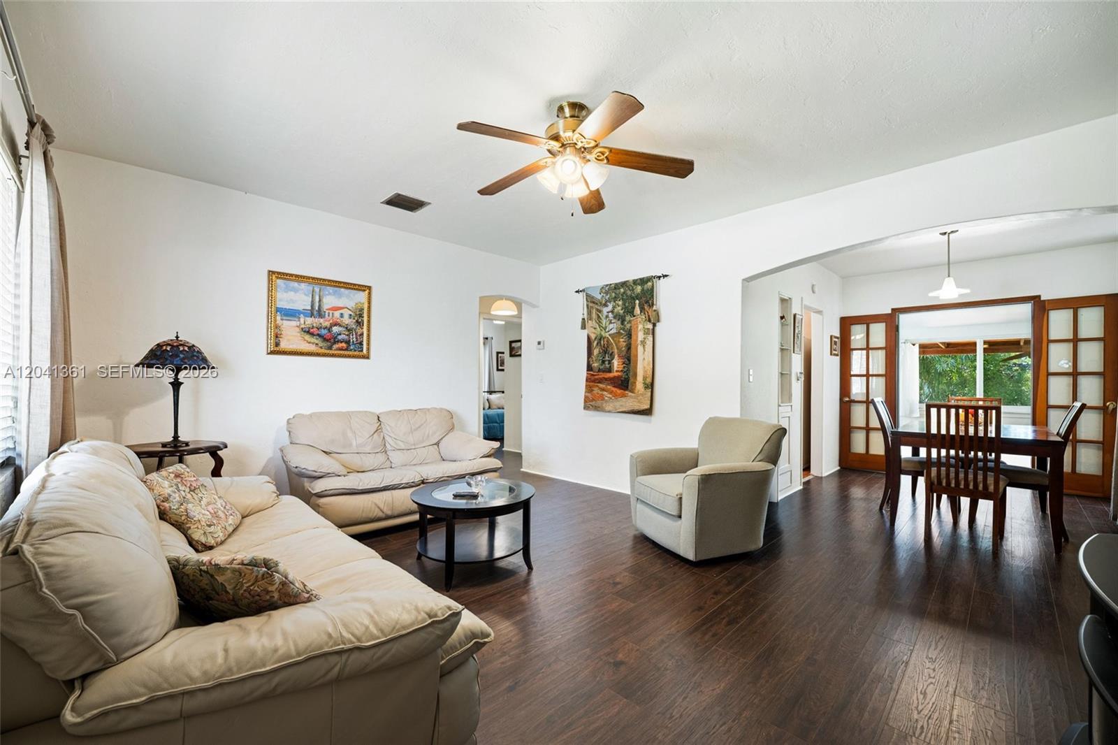 A living room with dark wood floors, white walls, leather sofas, and an adjacent dining area — 2750 NW 4th St, Miami FL 33125, MIAMI, FL