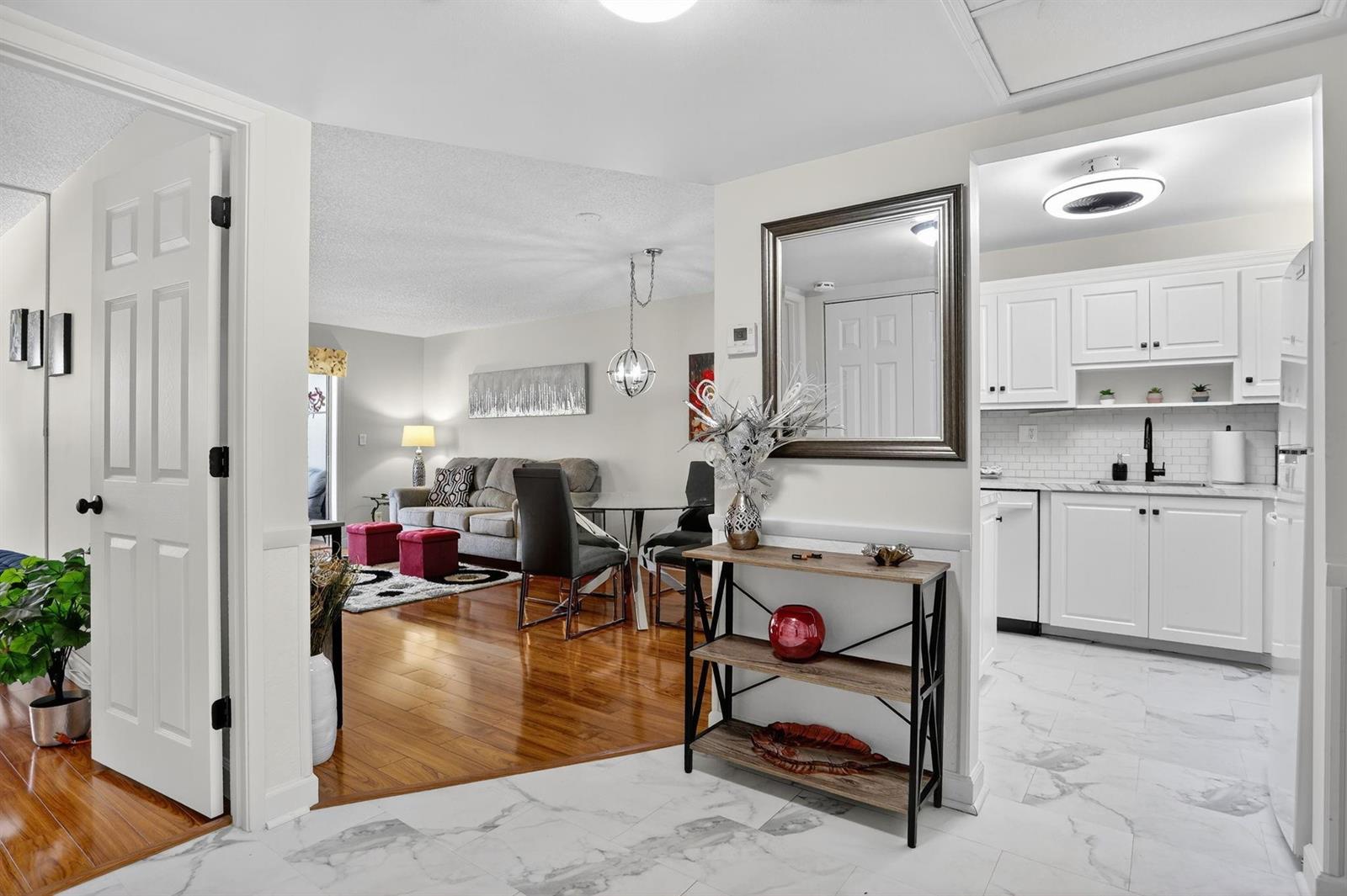 A view from a white-tiled entryway into a living area with hardwood floors — 5640 SW 3rd Place # 208, Margate FL 33068, MARGATE, FL