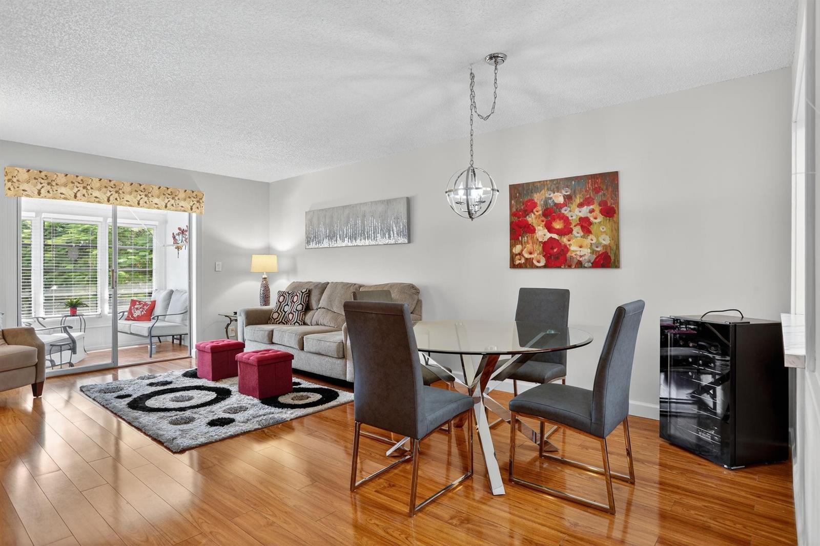 A living and dining area features hardwood floors, a glass-top table, and a sliding door — 5640 SW 3rd Place # 208, Margate FL 33068, MARGATE, FL