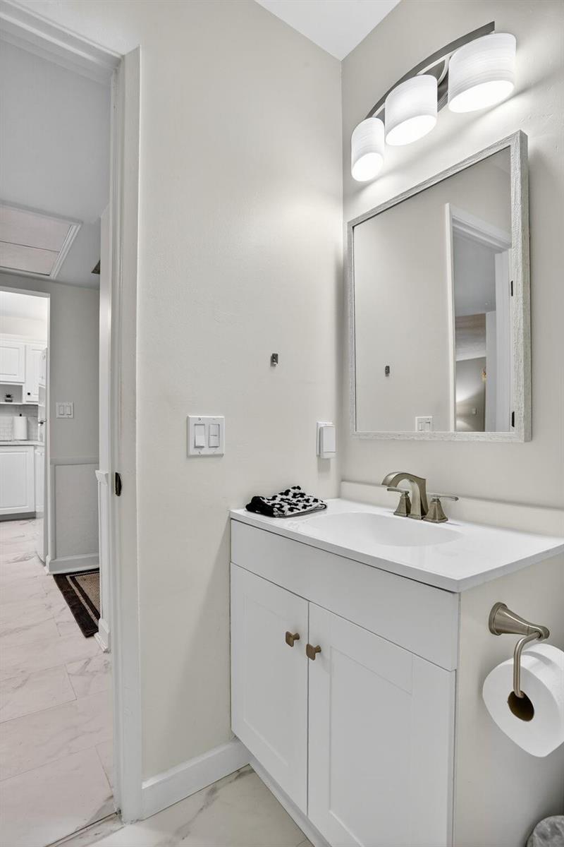 A bathroom vanity with a white cabinet, sink, mirror, and wall-mounted lighting fixture — 5640 SW 3rd Place # 208, Margate FL 33068, MARGATE, FL