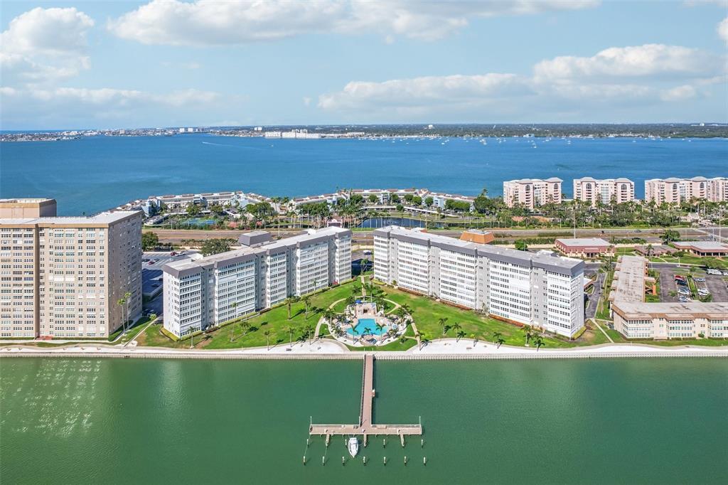 An aerial view shows several large apartment buildings situated along a waterfront with a pier — 5108 BRITTANY DRIVE S UNIT 805, ST PETERSBURG, FL