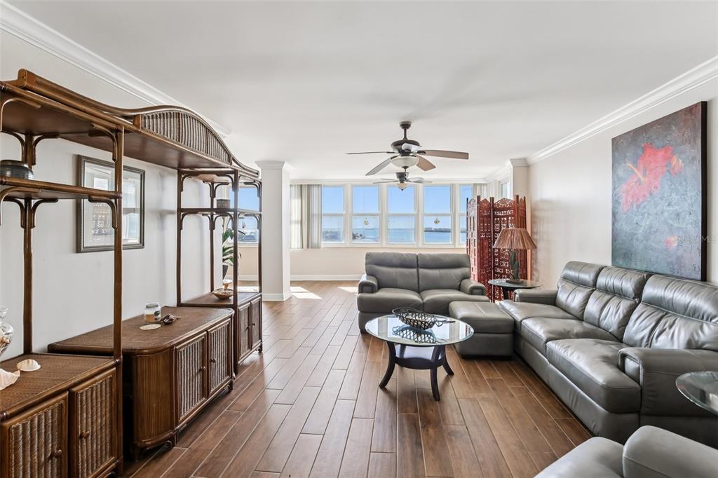 A living room with gray leather sofas, a glass coffee table, and ocean views — 5108 BRITTANY DRIVE S UNIT 805, ST PETERSBURG, FL