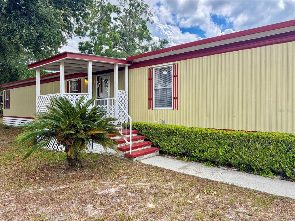 A mobile home with yellow metal siding, a red roof trim, and a small front porch — 10113 SE 24TH DRIVE, WEBSTER, FL