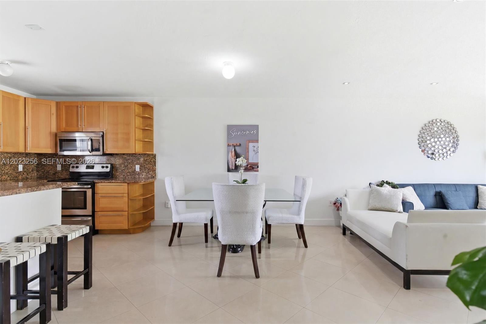 An open-concept living and dining area features a kitchen with light wood cabinets — 7680 SW 82nd St # H121, Miami FL 33143, MIAMI, FL