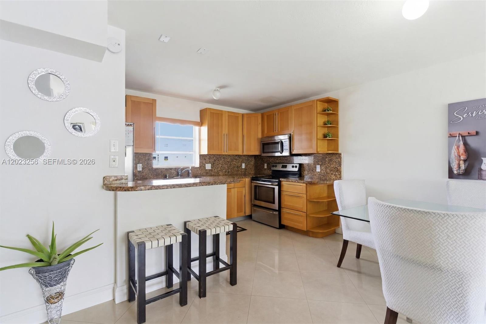 A kitchen features light wood cabinets, granite countertops, stainless steel appliances, and a breakfast bar — 7680 SW 82nd St # H121, Miami FL 33143, MIAMI, FL