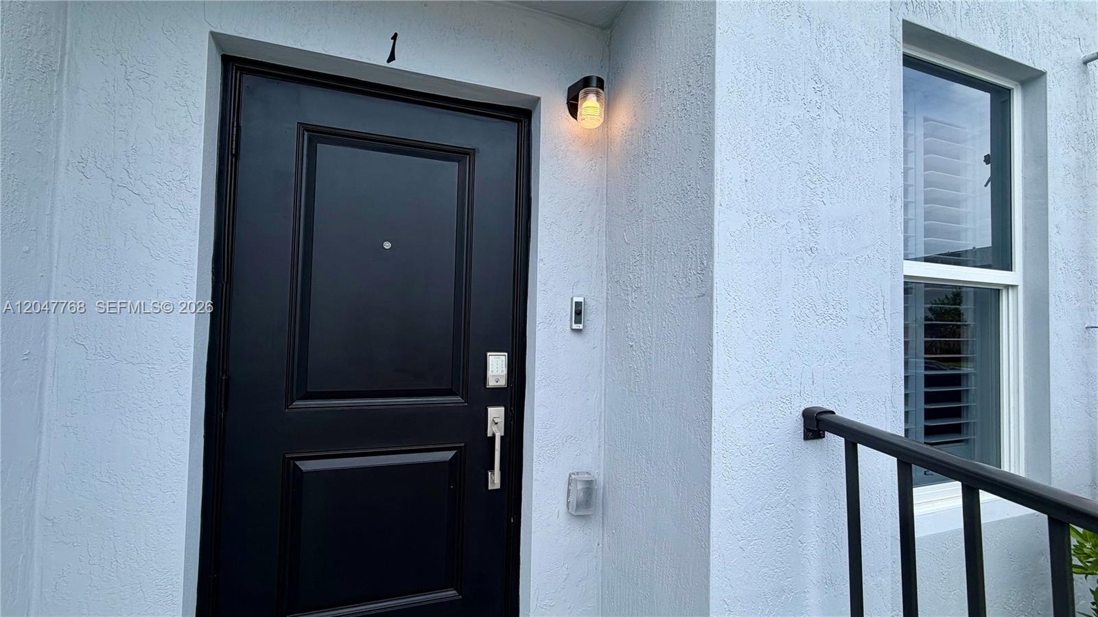 A black front door with a keypad lock sits beside a window and outdoor light — 15601 SW 280 # 1, Miami FL 33032, MIAMI, FL