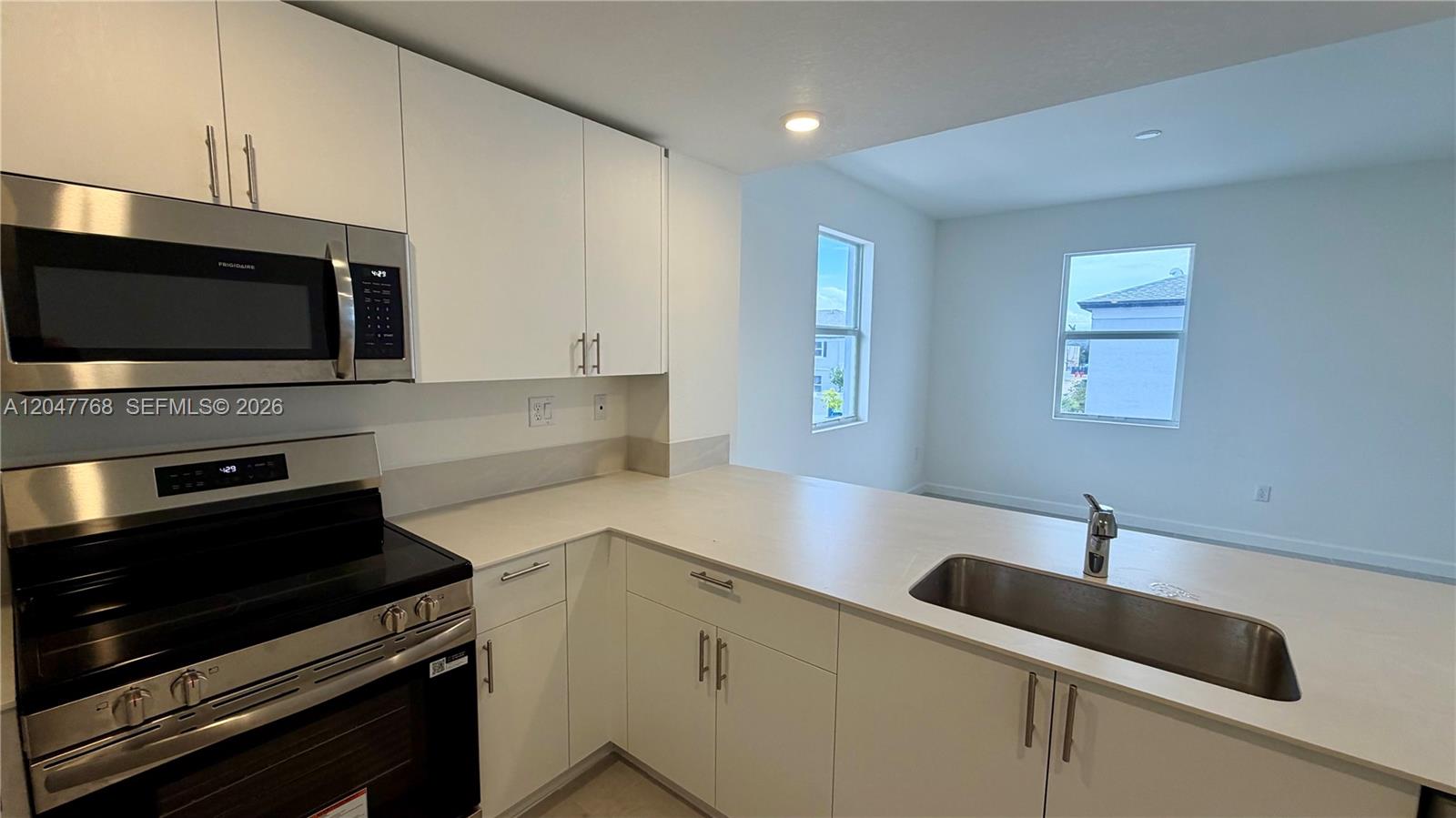 A modern kitchen features white cabinets, stainless steel appliances, and a peninsula with a sink — 15601 SW 280 # 1, Miami FL 33032, MIAMI, FL