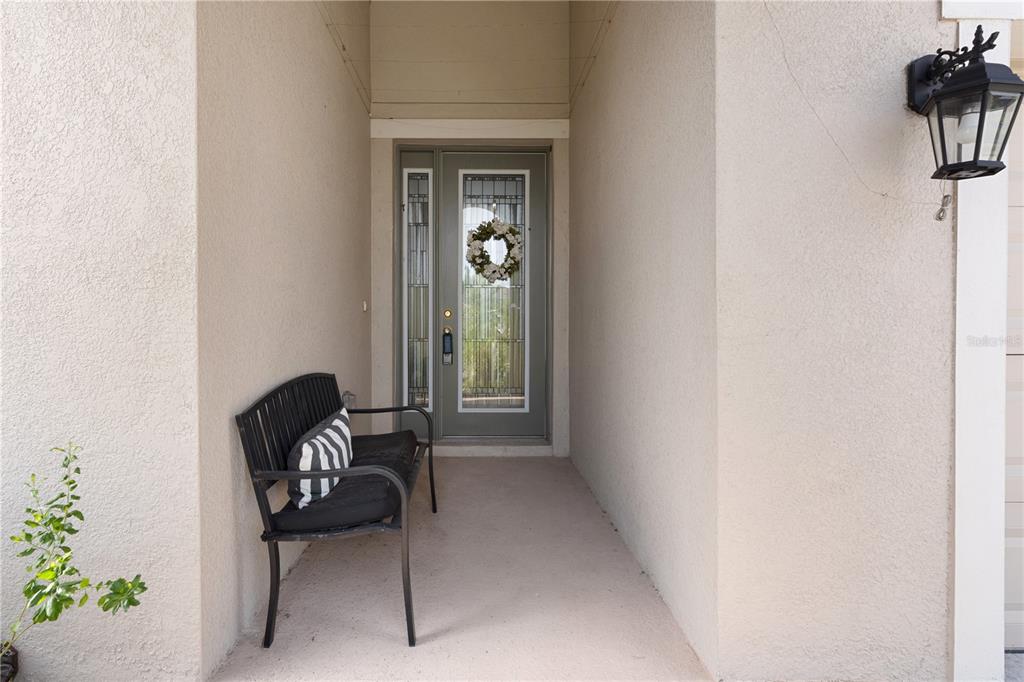 A covered front entryway features a black metal bench, a gray front door, and a lantern — 6227 GOLDEN NETTLE DRIVE, APOLLO BEACH, FL