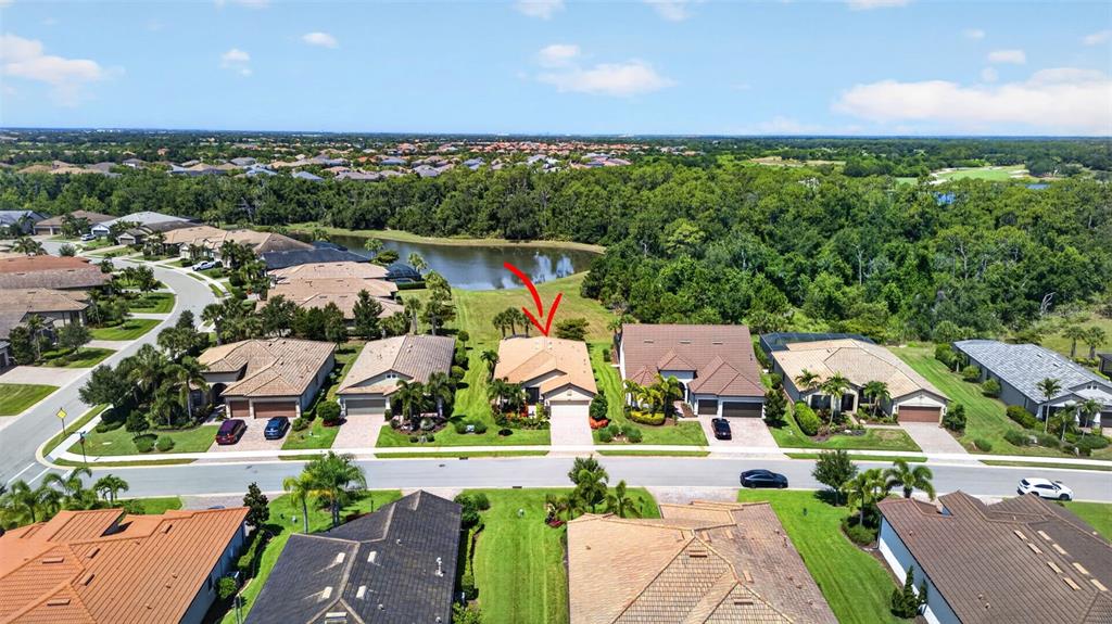 An aerial view shows a suburban residential street with houses, a lake, and trees — 16748 BLACKWATER TERRACE, BRADENTON, FL