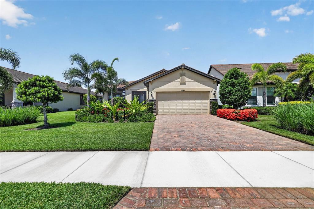 A single-story house with a paved driveway, a two-car garage, and landscaped front yard — 16748 BLACKWATER TERRACE, BRADENTON, FL