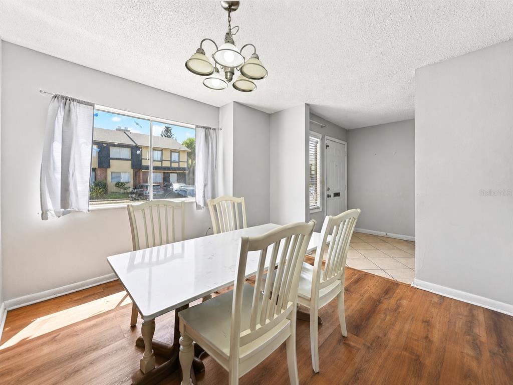 A dining room with a white table, four chairs, wood flooring, and a chandelier — 5137 PICADILLY CIRCUS COURT UNIT 3, ORLANDO, FL
