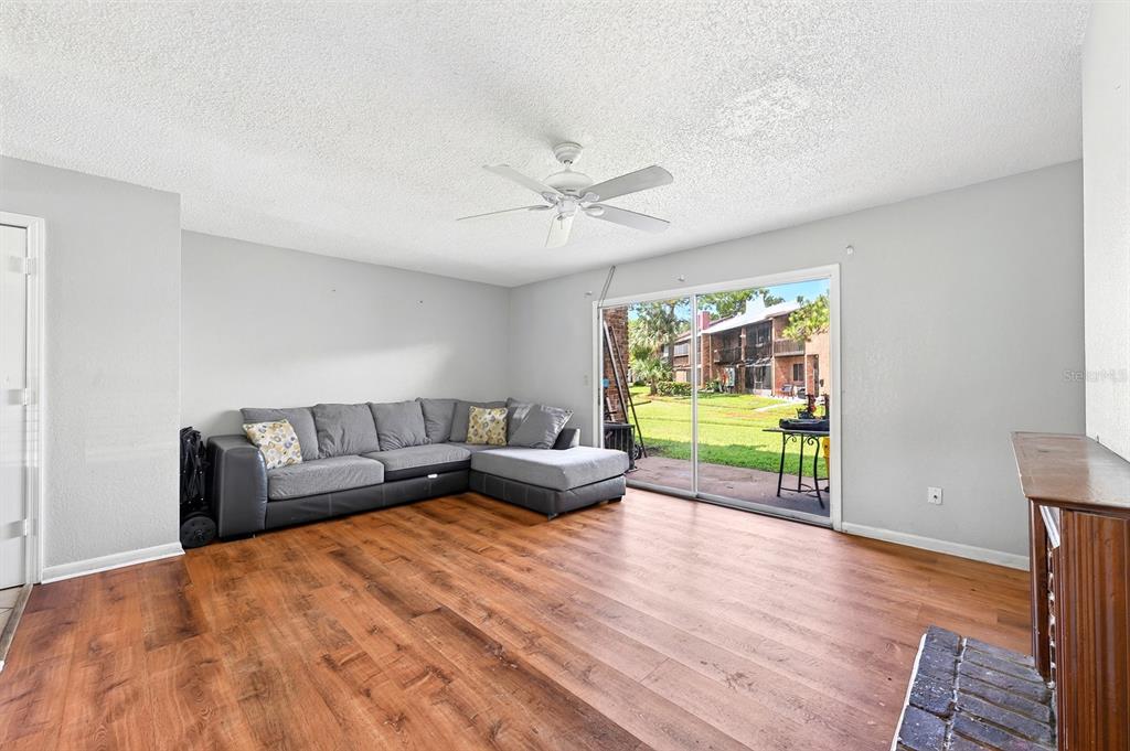 A living room features wood-look flooring, a gray sectional sofa, a ceiling fan, and sliding doors — 5137 PICADILLY CIRCUS COURT UNIT 3, ORLANDO, FL