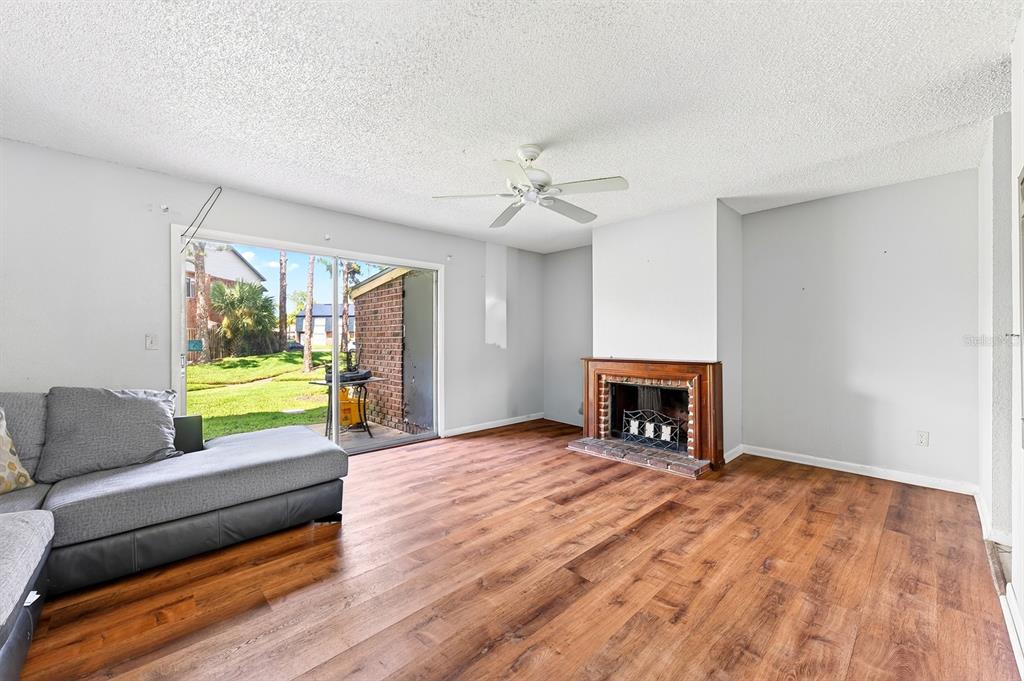 A living room features wood-look flooring, a fireplace, a ceiling fan, and a sliding glass door — 5137 PICADILLY CIRCUS COURT UNIT 3, ORLANDO, FL