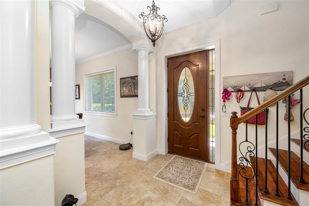 An entryway features tile flooring, a wooden front door, a staircase, and decorative columns — 1425 HILLSIDE LANDING DRIVE, TARPON SPRINGS, FL