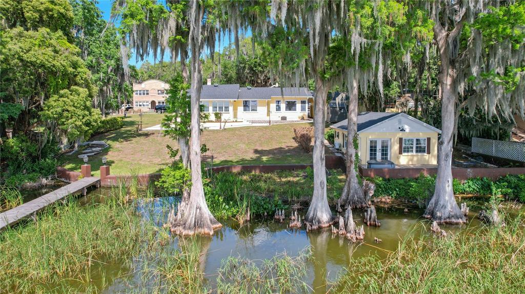 An exterior view of a yellow house with a detached garage beside a lake — 30437 ORANGE DRIVE, LEESBURG, FL