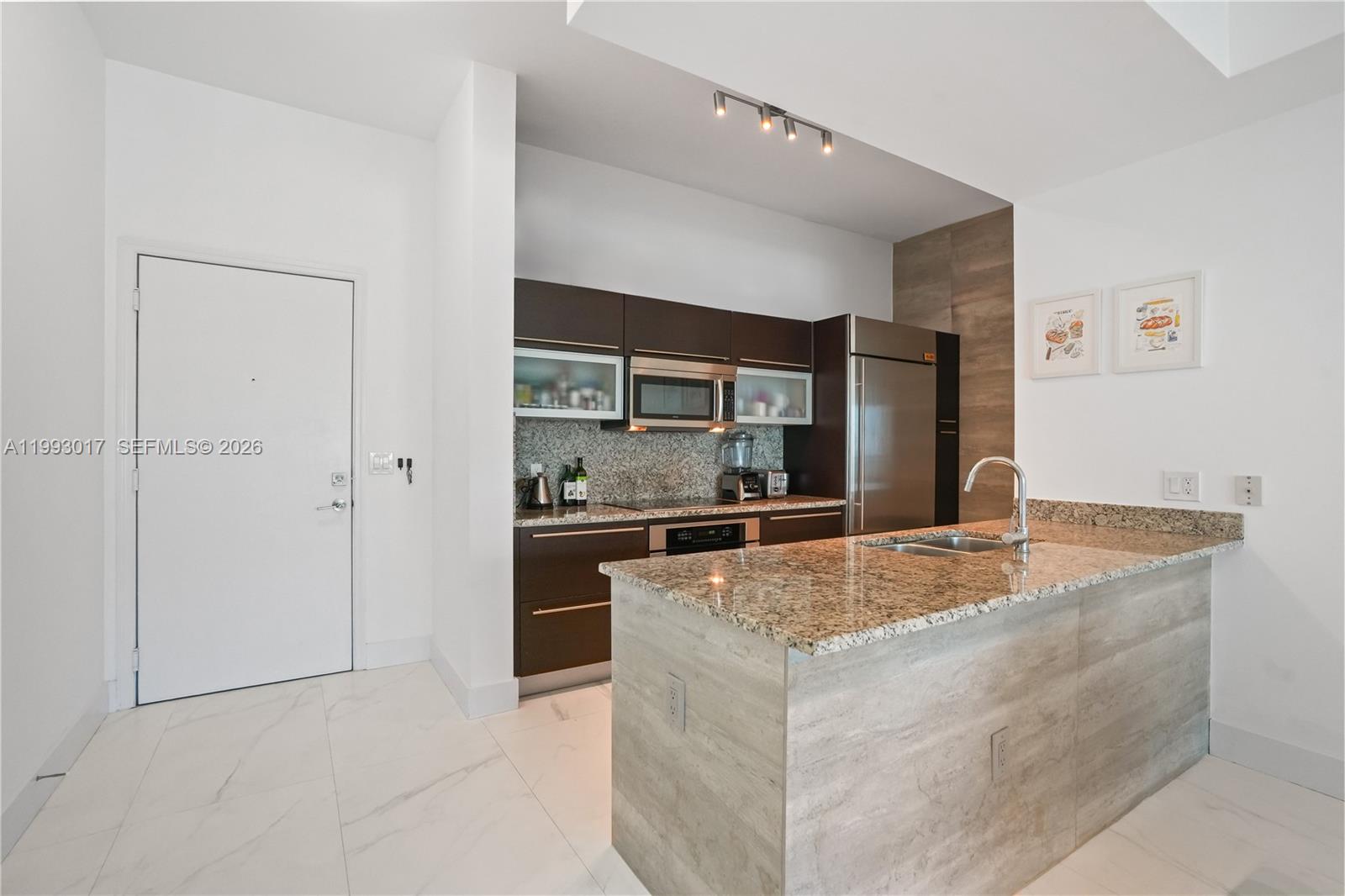 A modern kitchen features dark wood cabinetry, granite countertops, and a light wood-paneled island — 950 Brickell Bay Dr # 4101, Miami FL 33131, MIAMI, FL