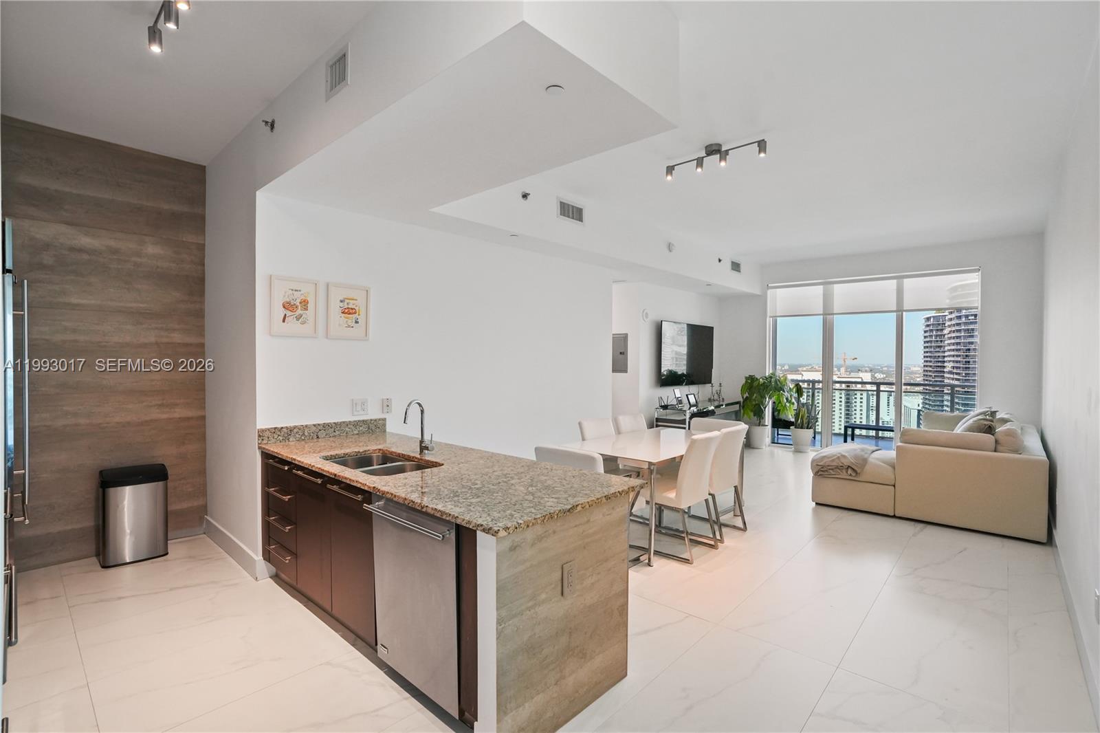 An open-concept kitchen with granite countertops overlooks a dining area and living room — 950 Brickell Bay Dr # 4101, Miami FL 33131, MIAMI, FL