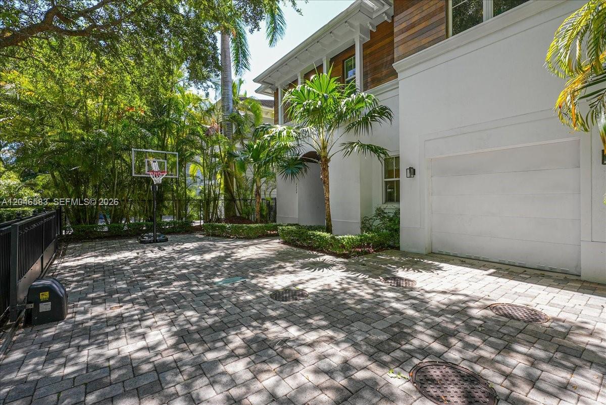 A paved driveway leads to a white house with a garage and a basketball hoop — 4734 Sunset Drive, Miami FL 33143, MIAMI, FL