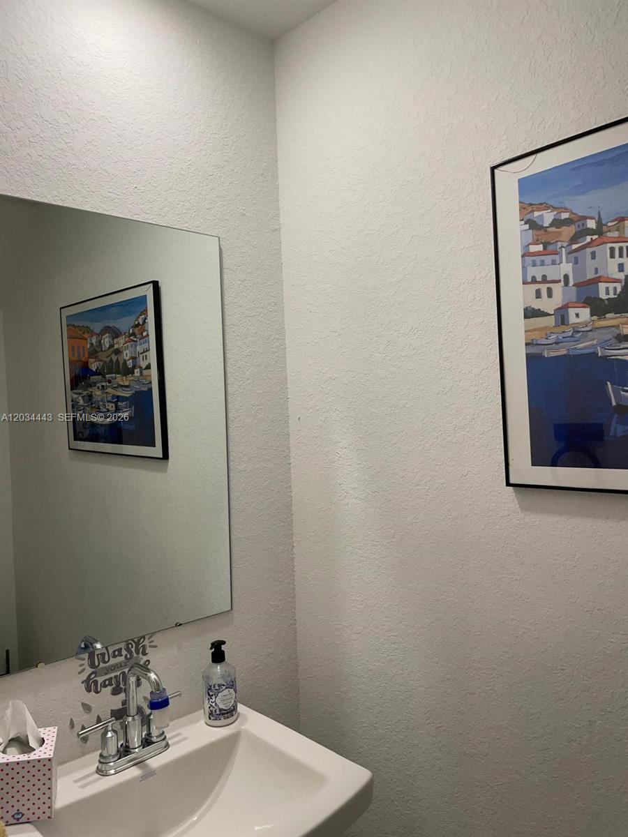 A bathroom features a white sink, a wall-mounted mirror, and framed coastal artwork — 556 NE 5th St, Florida City FL 33034, FLORIDA CITY, FL