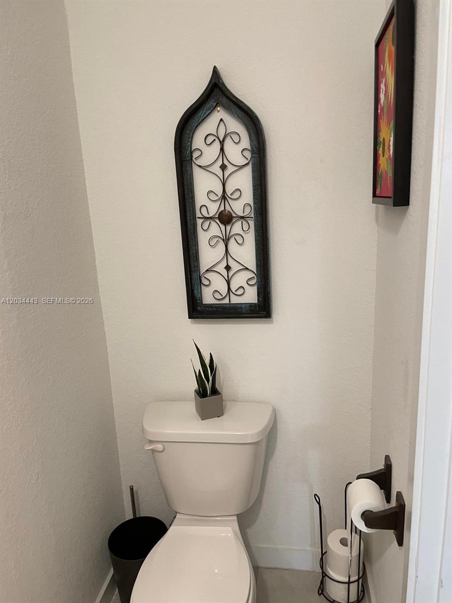 This bathroom features a toilet, a small potted plant, and a decorative wall hanging — 556 NE 5th St, Florida City FL 33034, FLORIDA CITY, FL