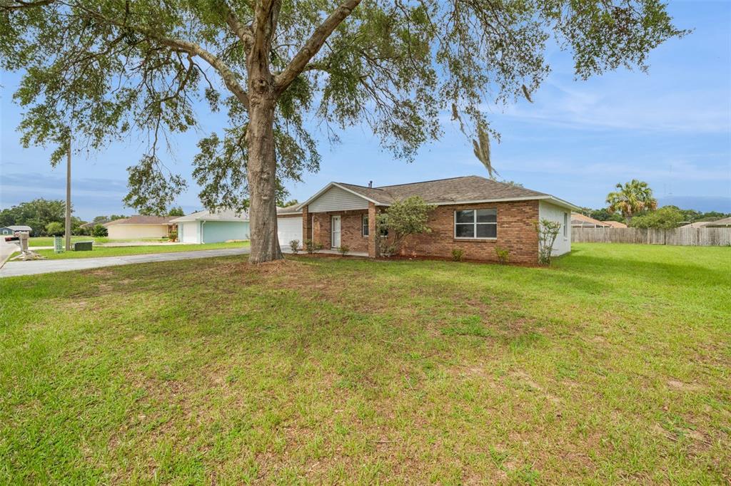 A living room features a gray sofa, two green armchairs, a coffee table, and wood-look flooring — 261 SE 61ST COURT, OCALA, FL
